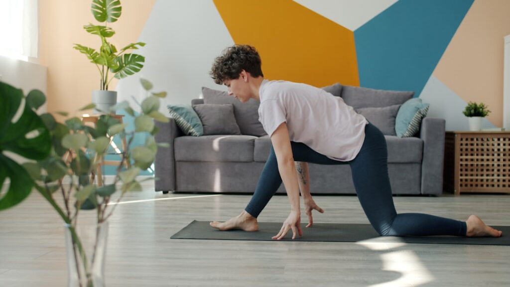 person stretching legs on yoga mat in bright living room